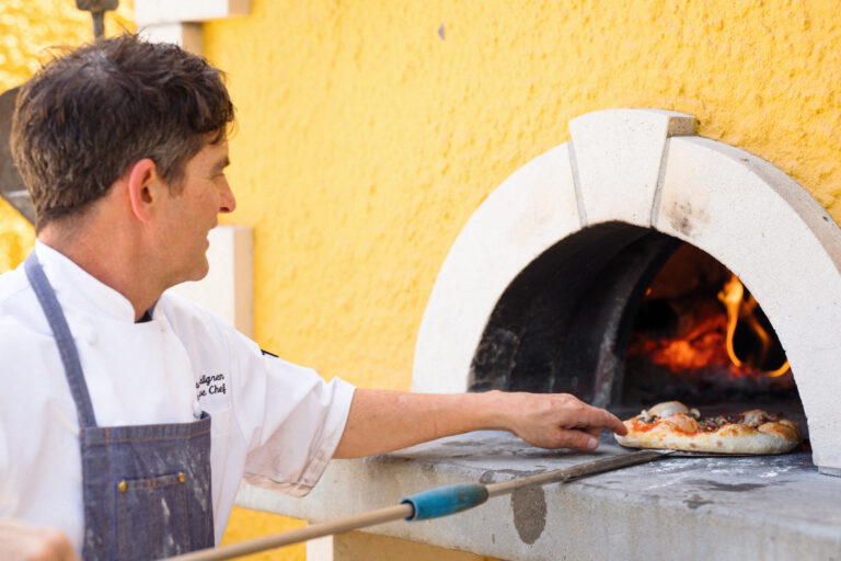 chef cooking pizza in wood fired oven