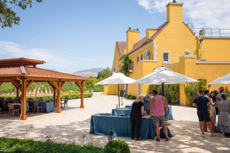 umbrellas, tables and pergola on terrace with yellow chateau in background