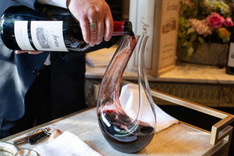 sommelier pouring magnum of cabernet wine into a decanter