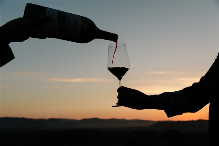 silhouette image of cabernet sauvignon being poured into a wine glass at sunset