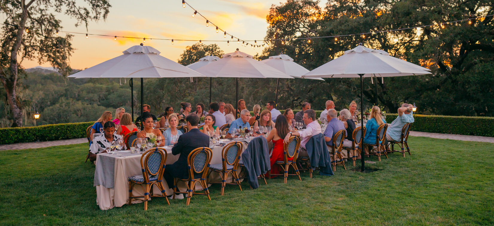 long table for starlight supper set on winery grass terrace lawn under white umbrellas