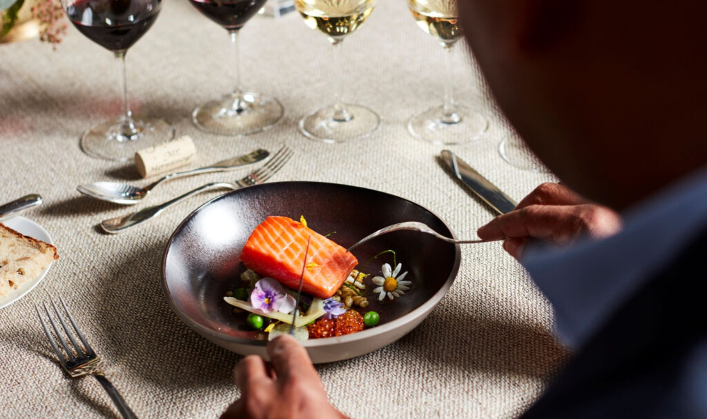 A guest about to cut a piece of salmon in at a formal dinner in the Jordan Winery dining room