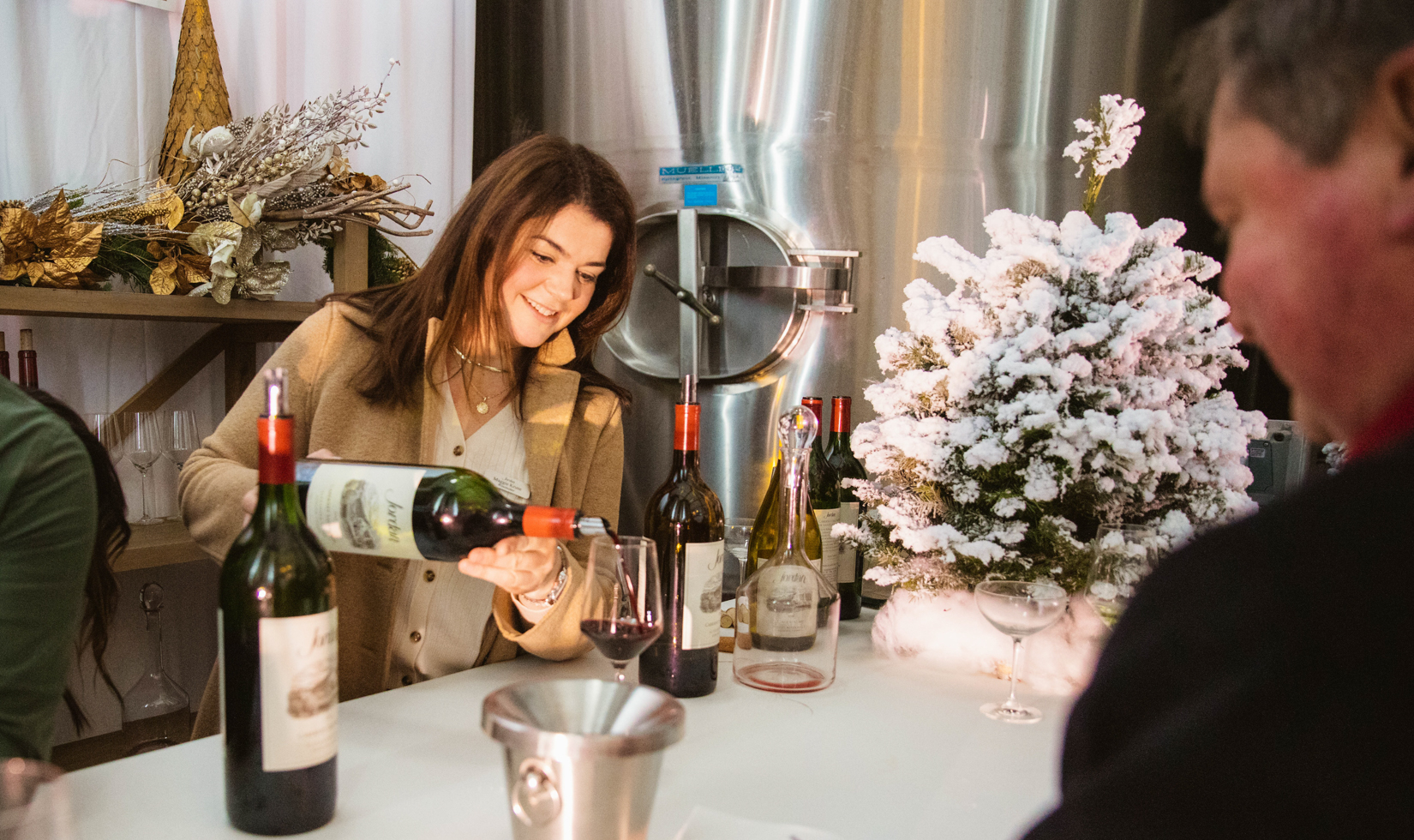 winemaker maggie kruse pouring jordan cabernet sauvignon behind bar decorated for christmas