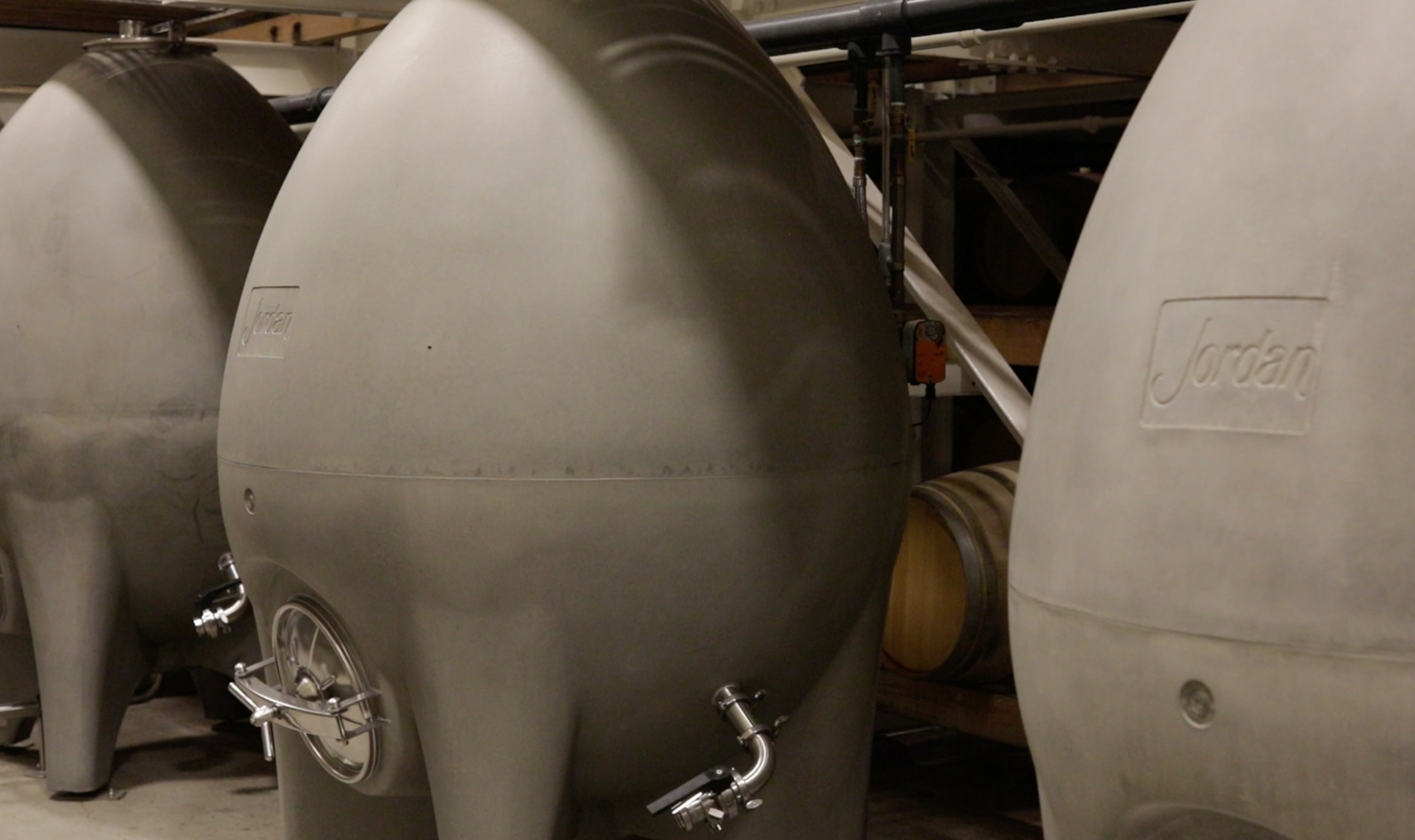 three large concrete egg fermentation vessels in wine barrel room