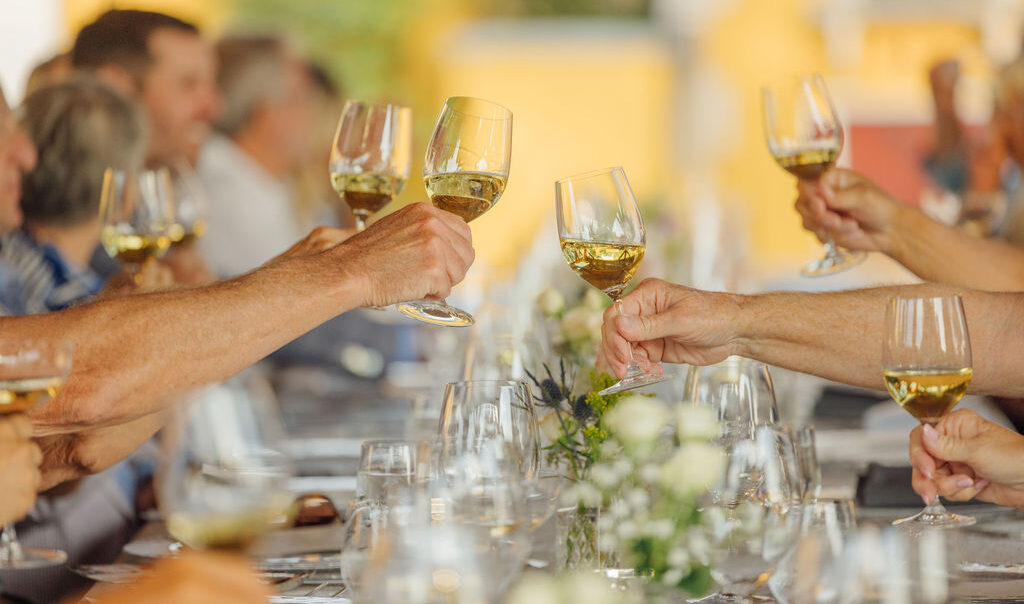 group of chardonnay glasses toasting at an outdoor dinner table