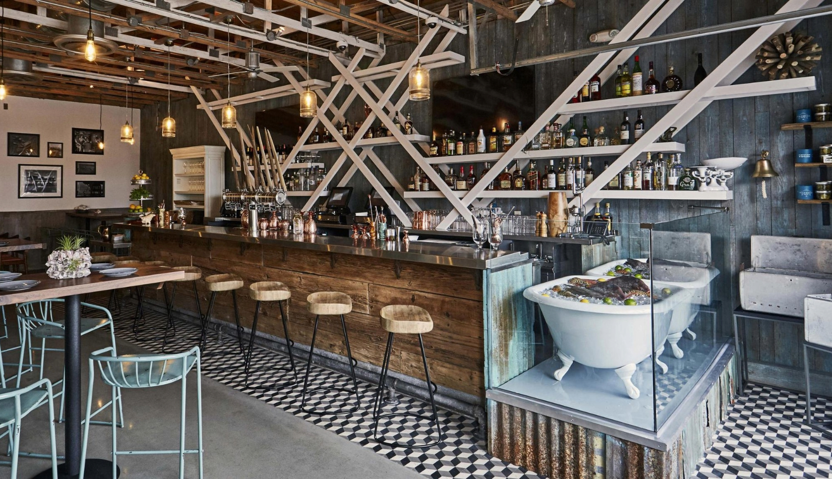 bar at stiltsville restaurant with driftwood-style wood bar next to a bathtub filled with ice and fresh seafood