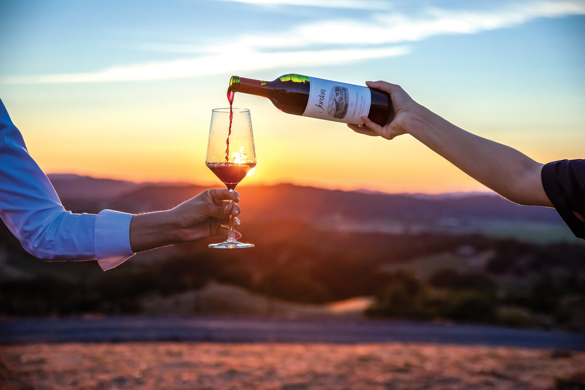 pouring a glass of jordan cabernet sauvignon with a vista sunset in the background