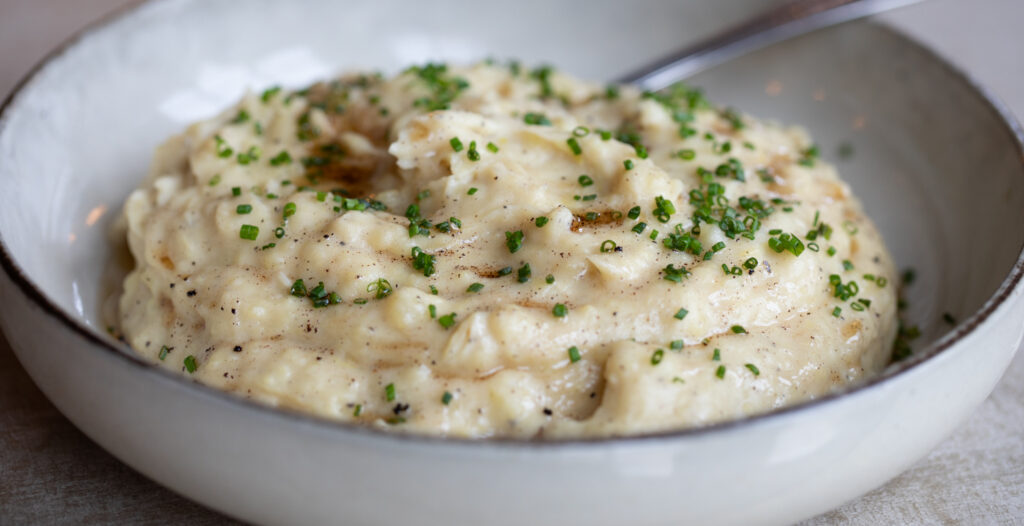 close up of bowl of mashed potatoes with brown butter