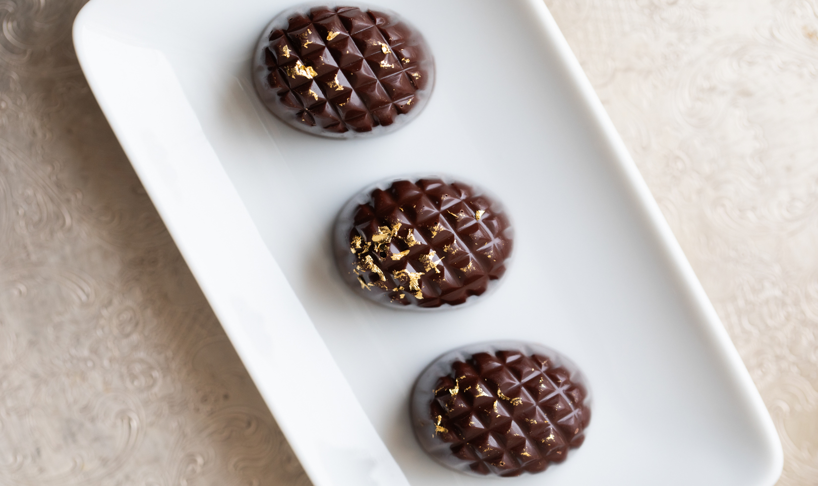 three chocolate truffles on white plate