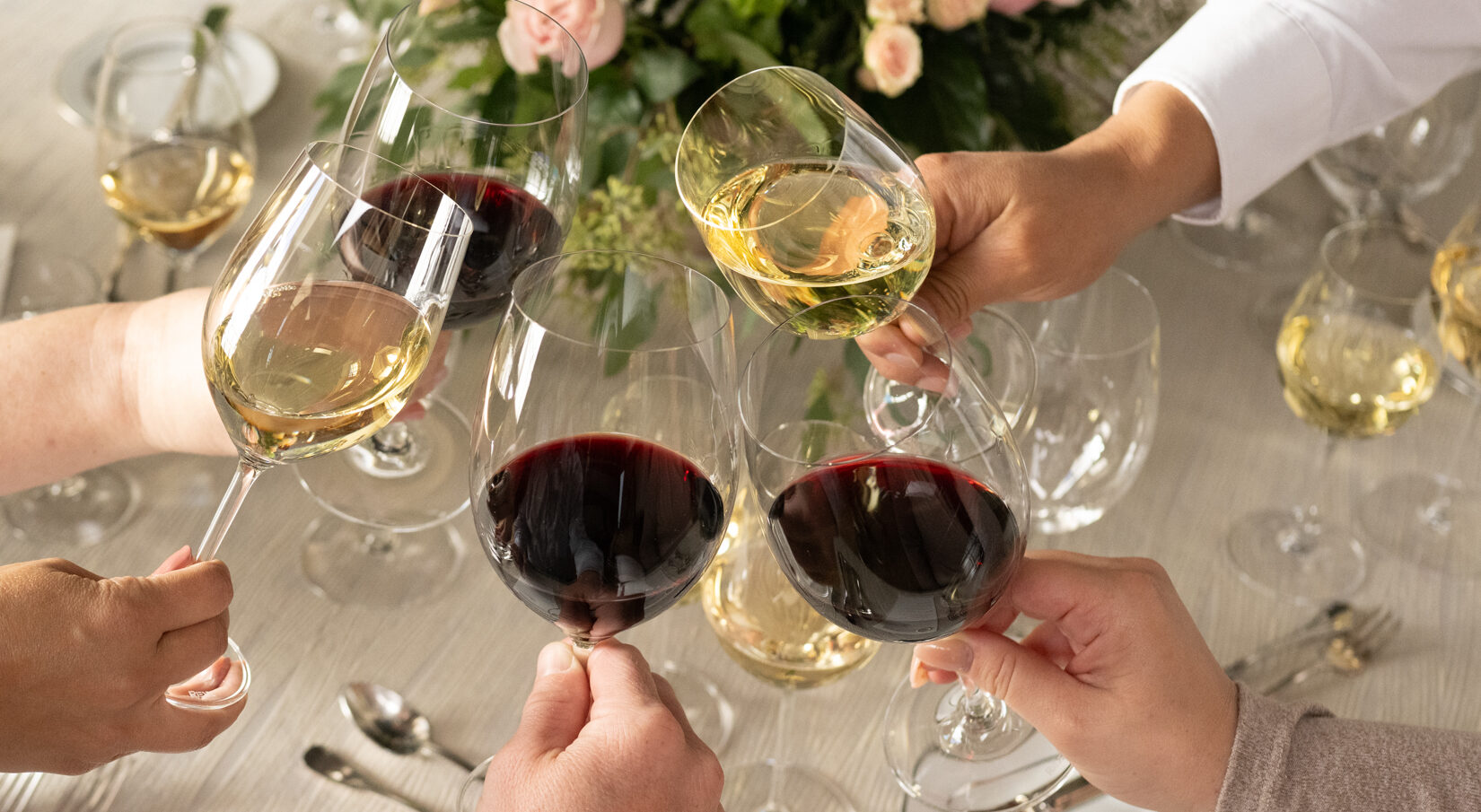 glasses of white wine and red wine toasting around a table