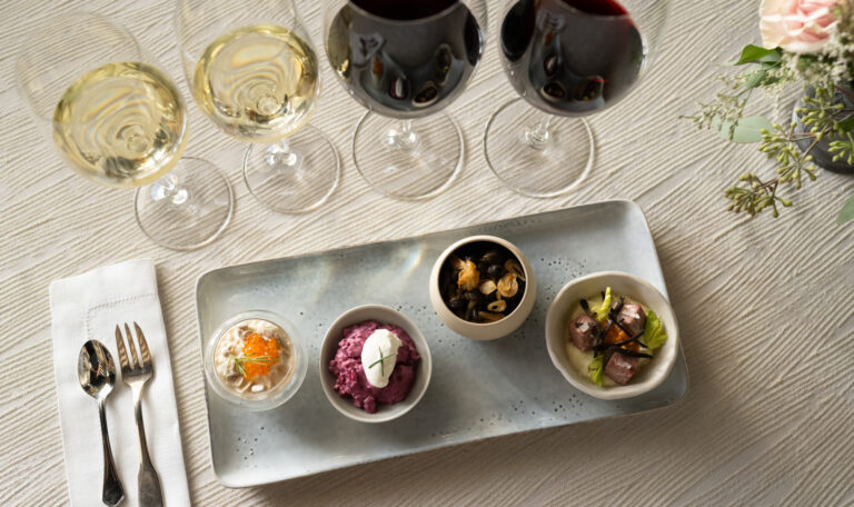 four appetizers on plate with four wines paired on table