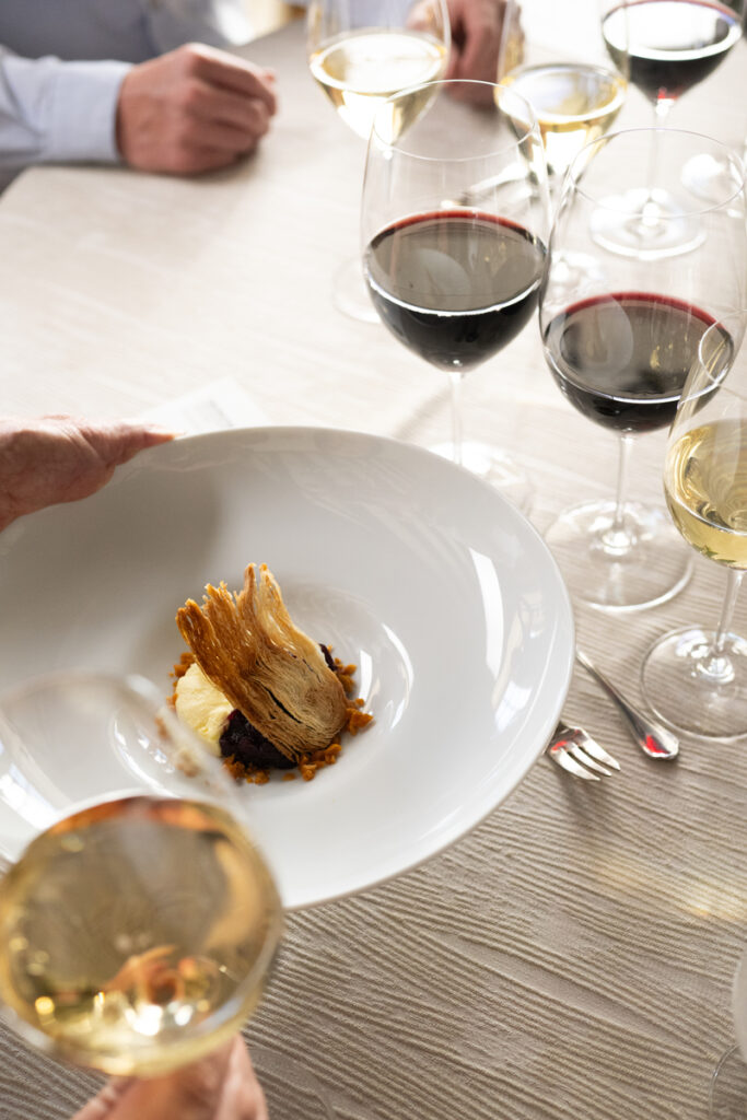 server placing entree on table in front of glasses of red and white wine